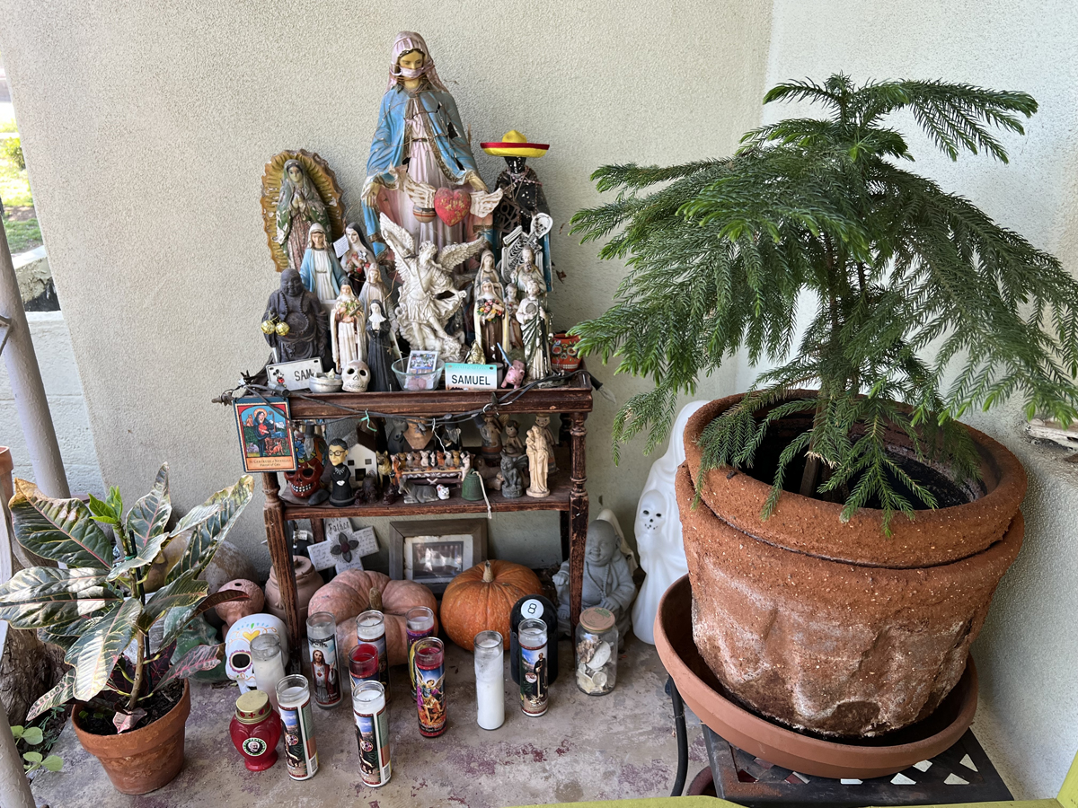 A tenderly crafted altar on Annie Lopez's front porch, featuring religious figurines, prayer candles, prayer cards, pumpkins and other ephemera.