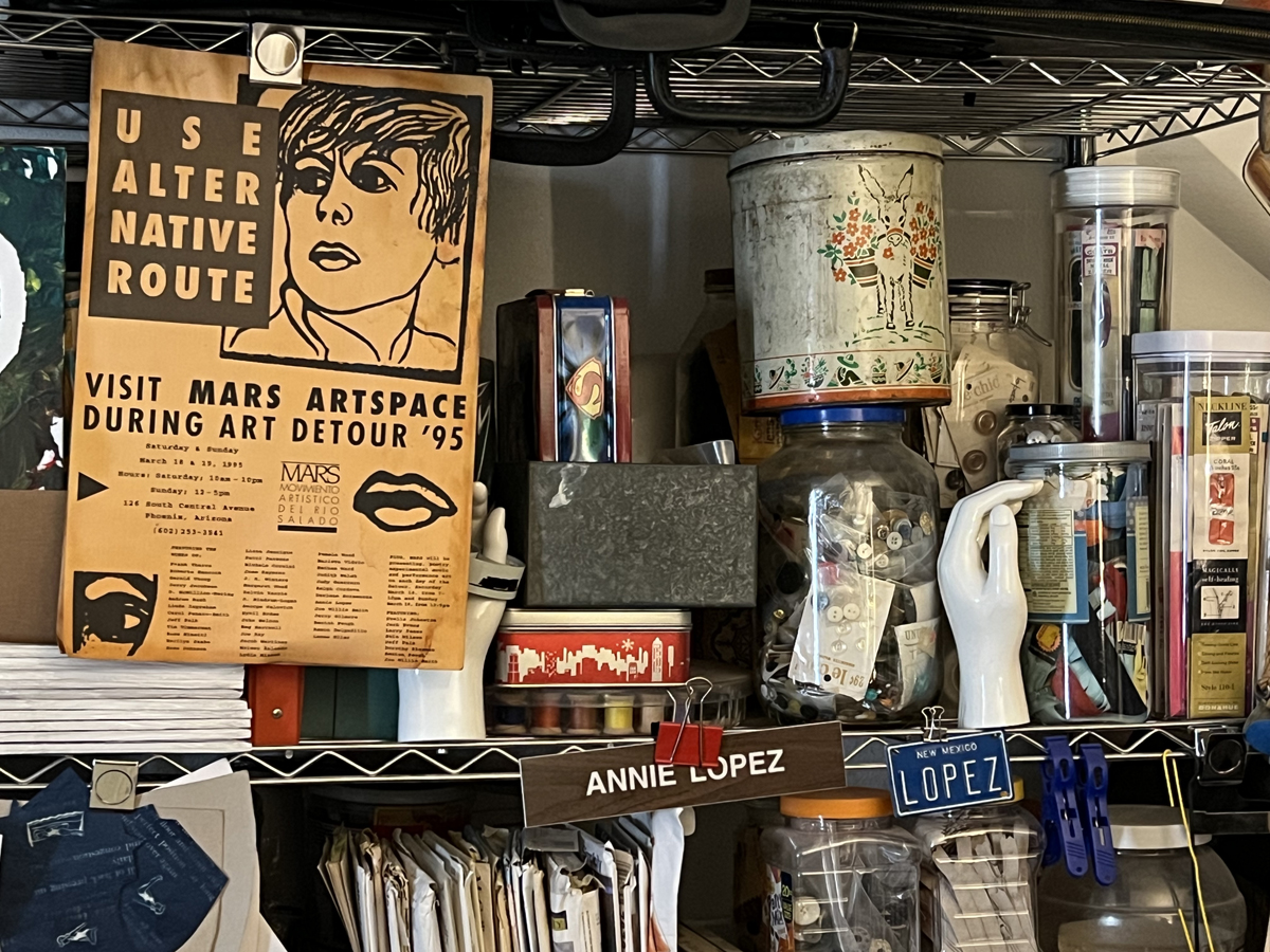 A tight view of Annie Lopez's jam-packed studio, featuring nametags, publications, and a 1995 poster from MARS art space.