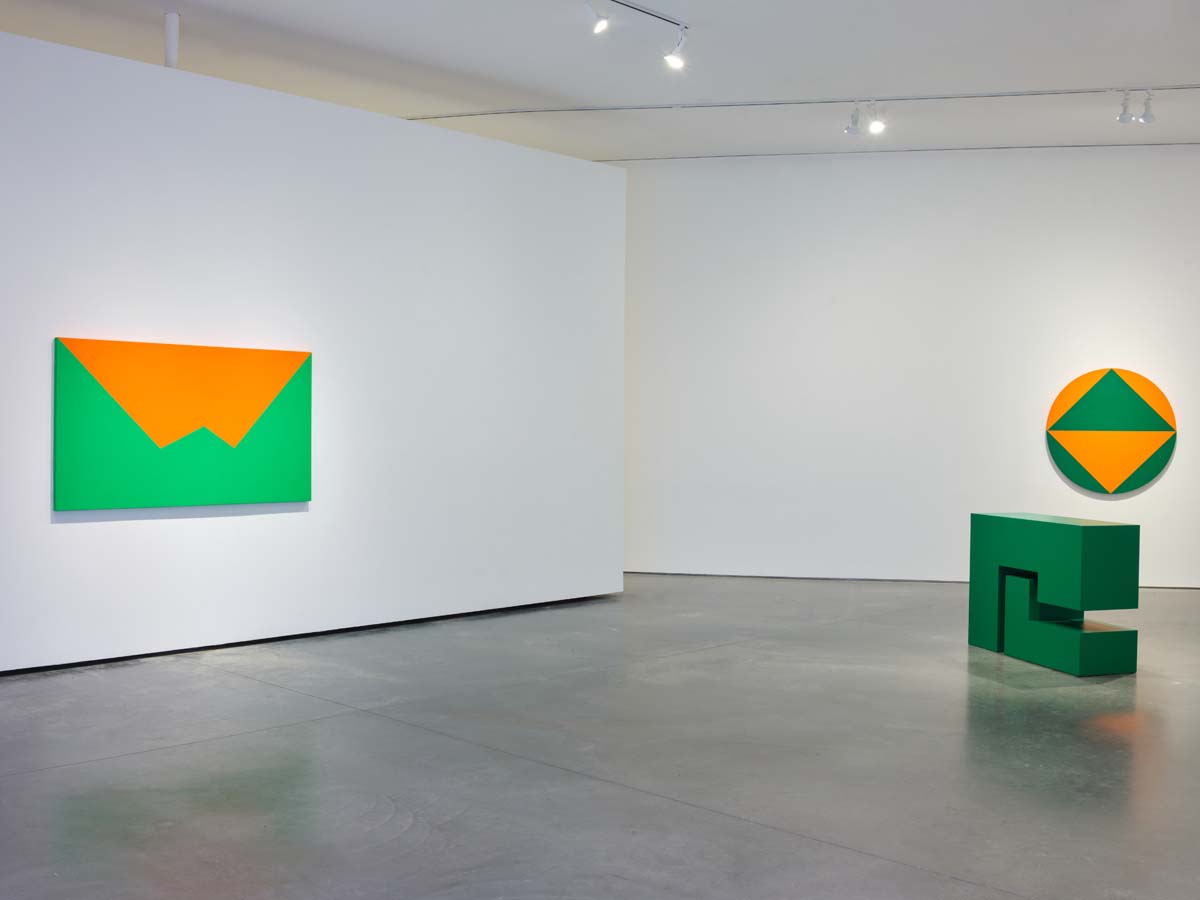 An orange and green minimal painting on the left and a monochrome green geometric sculpture on the right.