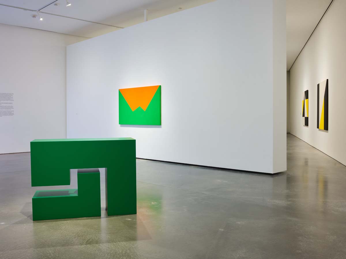 Installation view of SITE Santa Fe show of Carmen Herrera, with green geometric sculpture in the foreground.