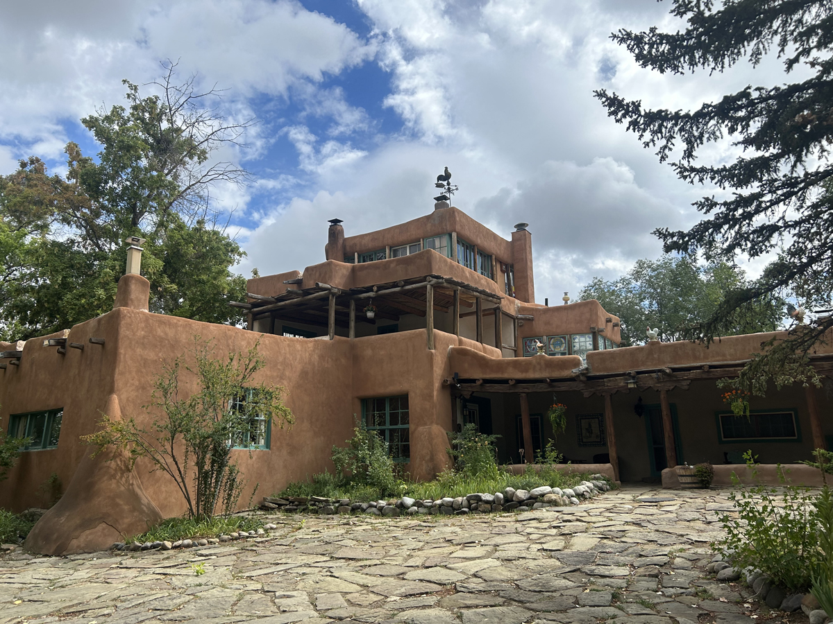 The historic home of Mabel Dodge Luhan and Tony Luhan in Taos, New Mexico is a towering adobe fortification with rooster figurines perched along its roof.