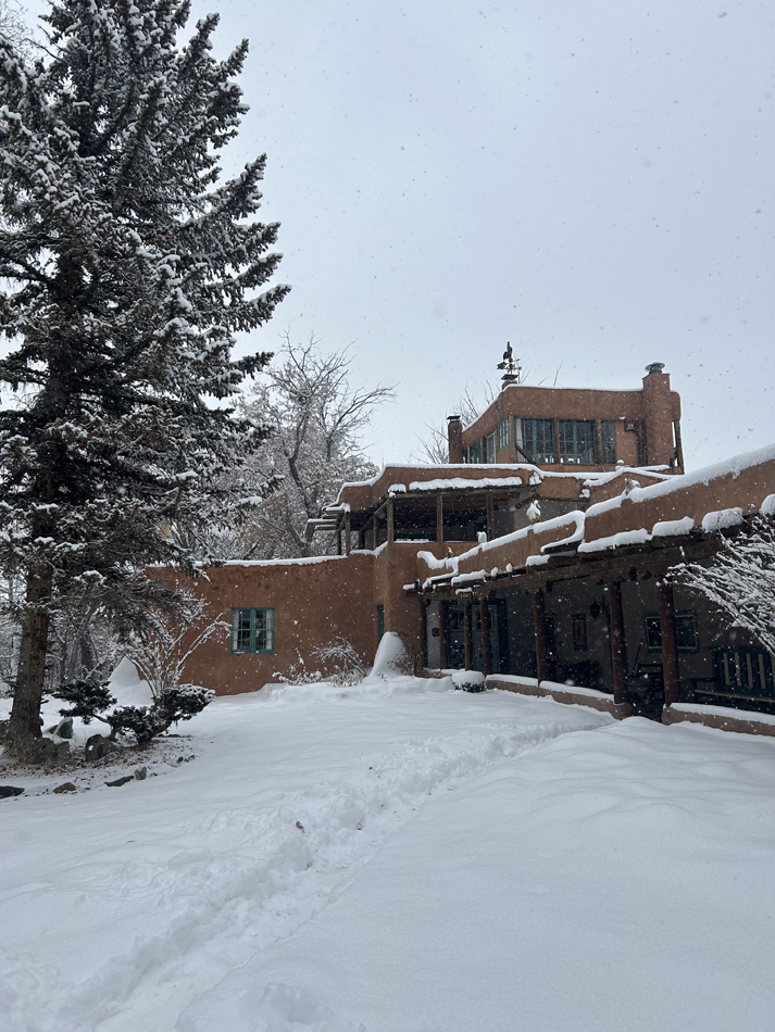 The Mabel Dodge Luhan House, a mansion in a Pueblo Revival style, is covered in snow.