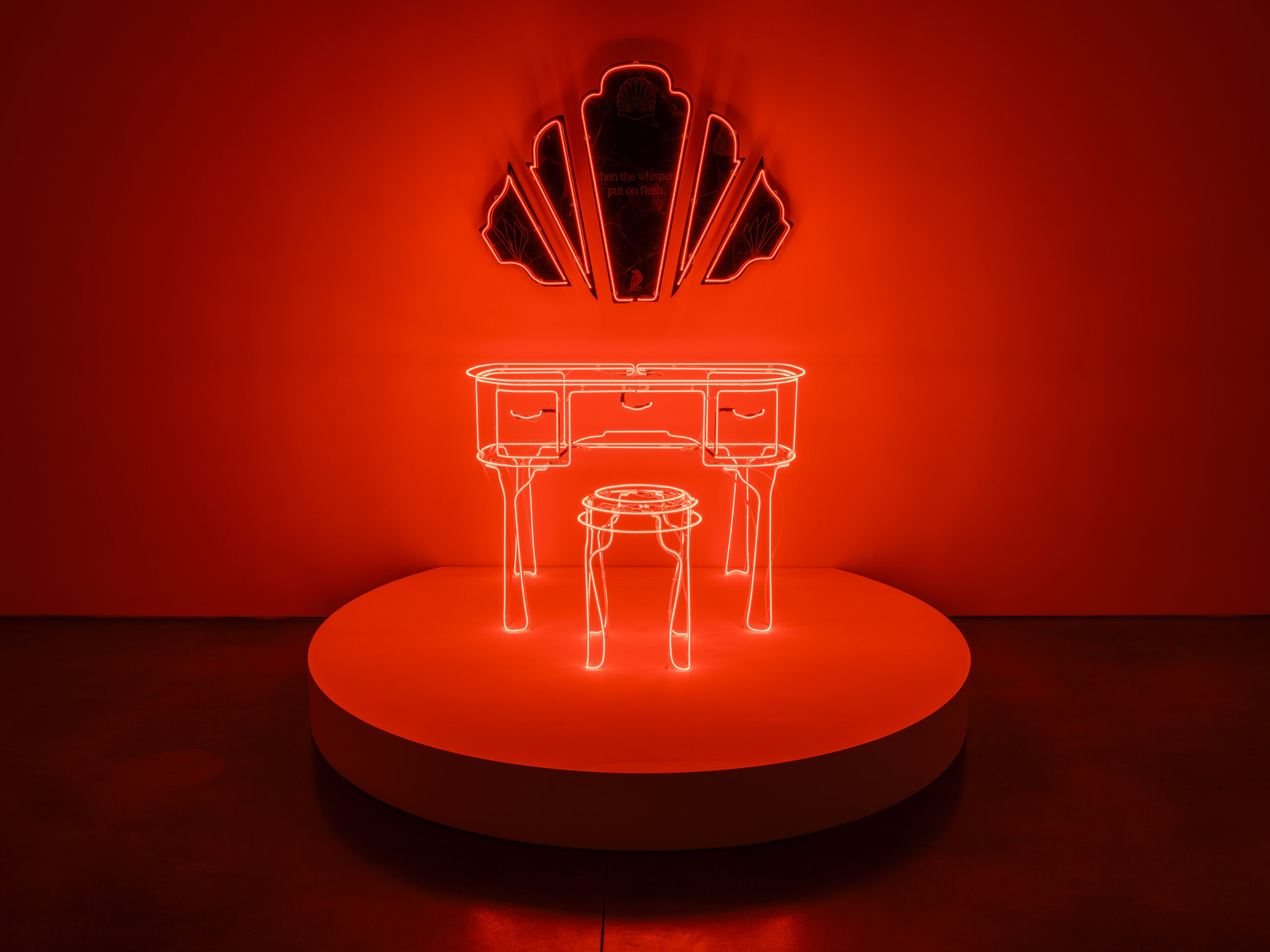 Installation view of a red neon sculpture by Ja-Tovia Gary, depicting a boudoir with angular mirrors hanging above it.