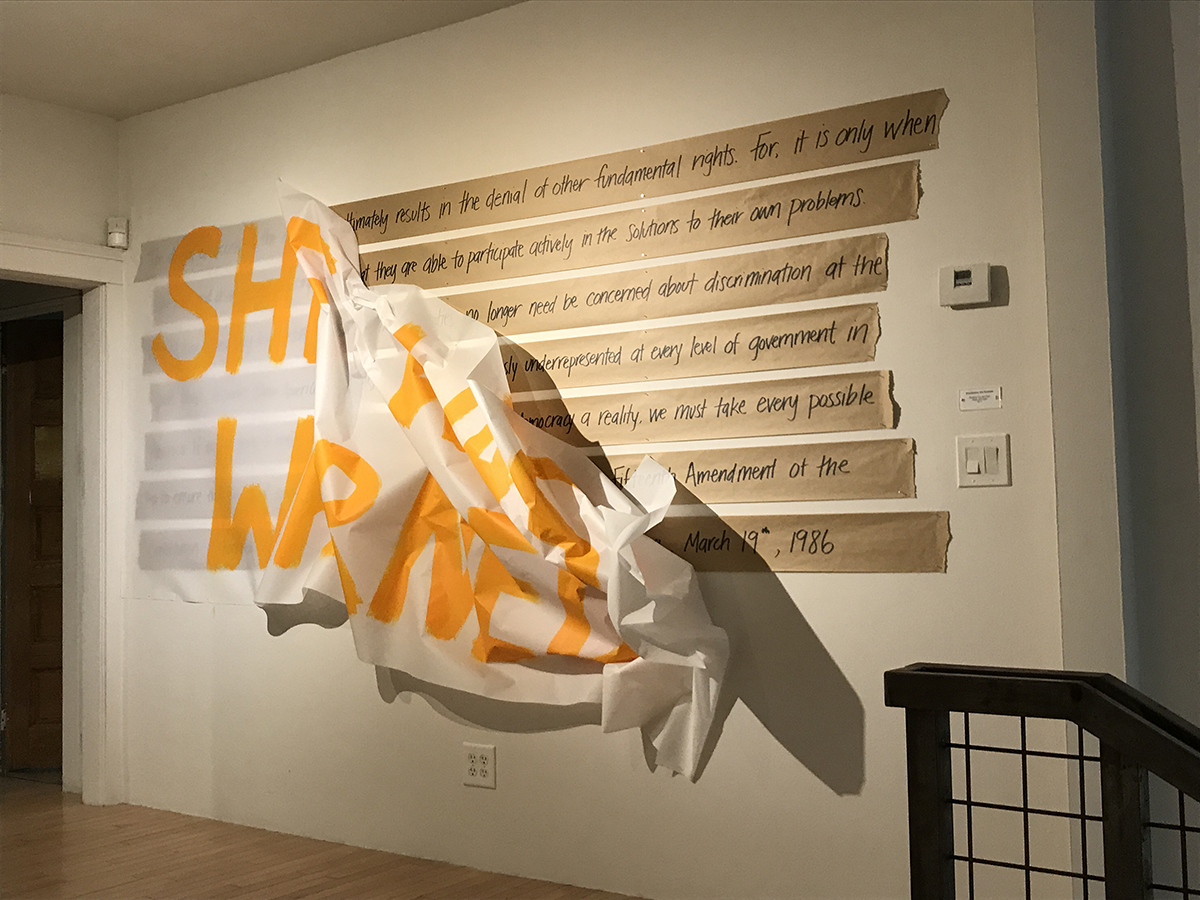 An artwork by Christina You-sun Park titled Nevertheless She Persisted features a banner peeling off a wall to reveal the words of a historic speech.