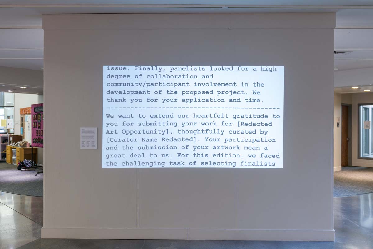 Text of rejection letters in black courier font projected on a wall in the exhibition I Regret to Inform You: Rejected Public Art.