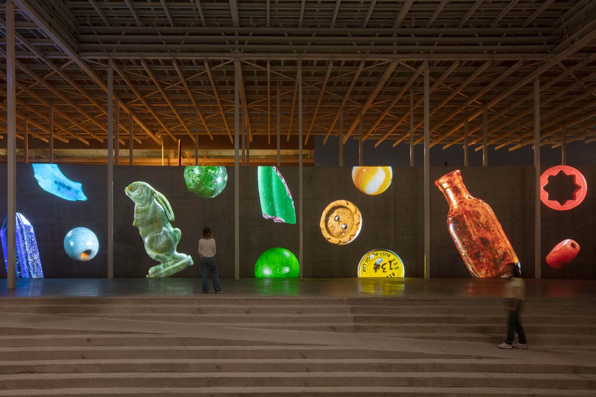 A video projection of various small items in a rainbow spectrum across several screens in the Moody Amphitheater in Austin, TX.