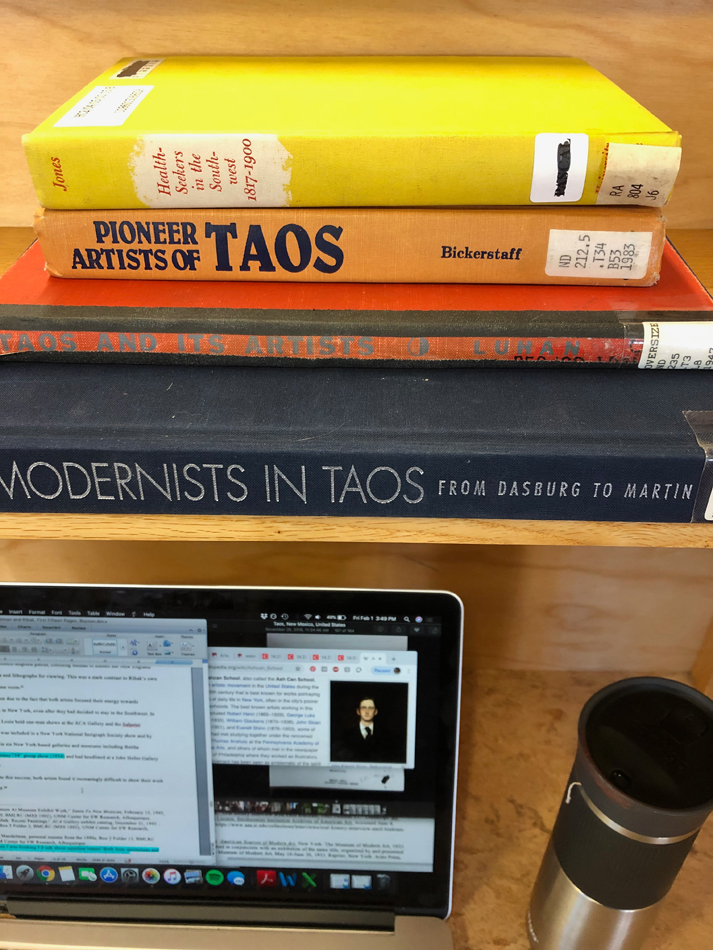 A stack of books about the art history of Taos, New Mexico.