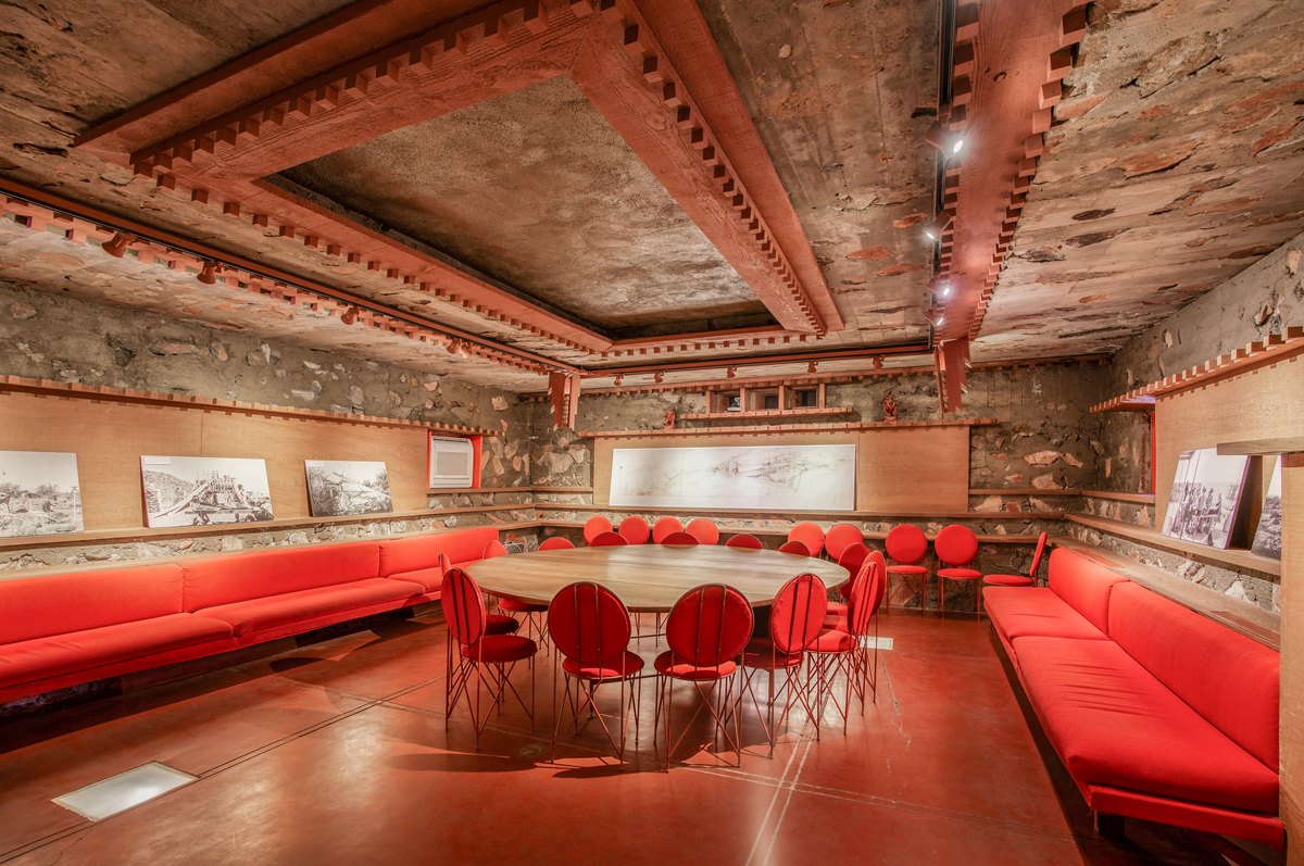 A circular table clustered with red chairs in Frank Lloyd Wright's Southwestern outpost Taliesen West.