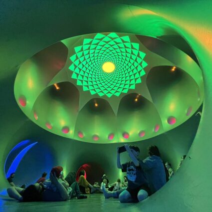 An inflatable luminarium chamber bathed in green light and a mandala-like oculus at the top.