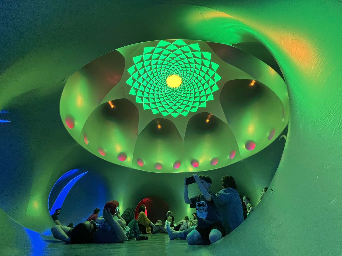 An inflatable luminarium chamber bathed in green light and a mandala-like oculus at the top.