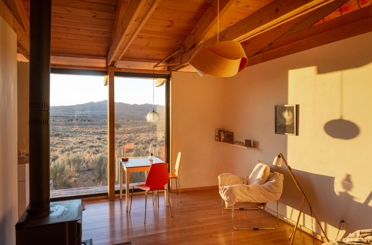 The interior of a cabin with a large window, lit by the sunset. The Montello Foundation is just one of the Southwest artist residencies featured in Southwest Contemporary's Fall 2024-Winter 2025 guide to forthcoming residency deadlines.