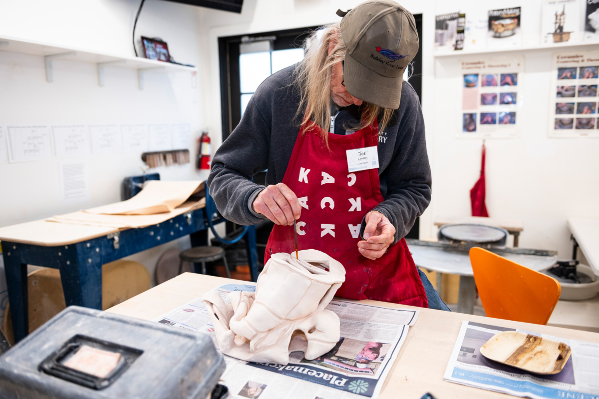 A person in a red apron works on a sculptural vessel in a ceramics studio. Kimball Art Center is just one of the venues featured in this year's Southwest Holiday Gift Guide from Southwest Contemporary.