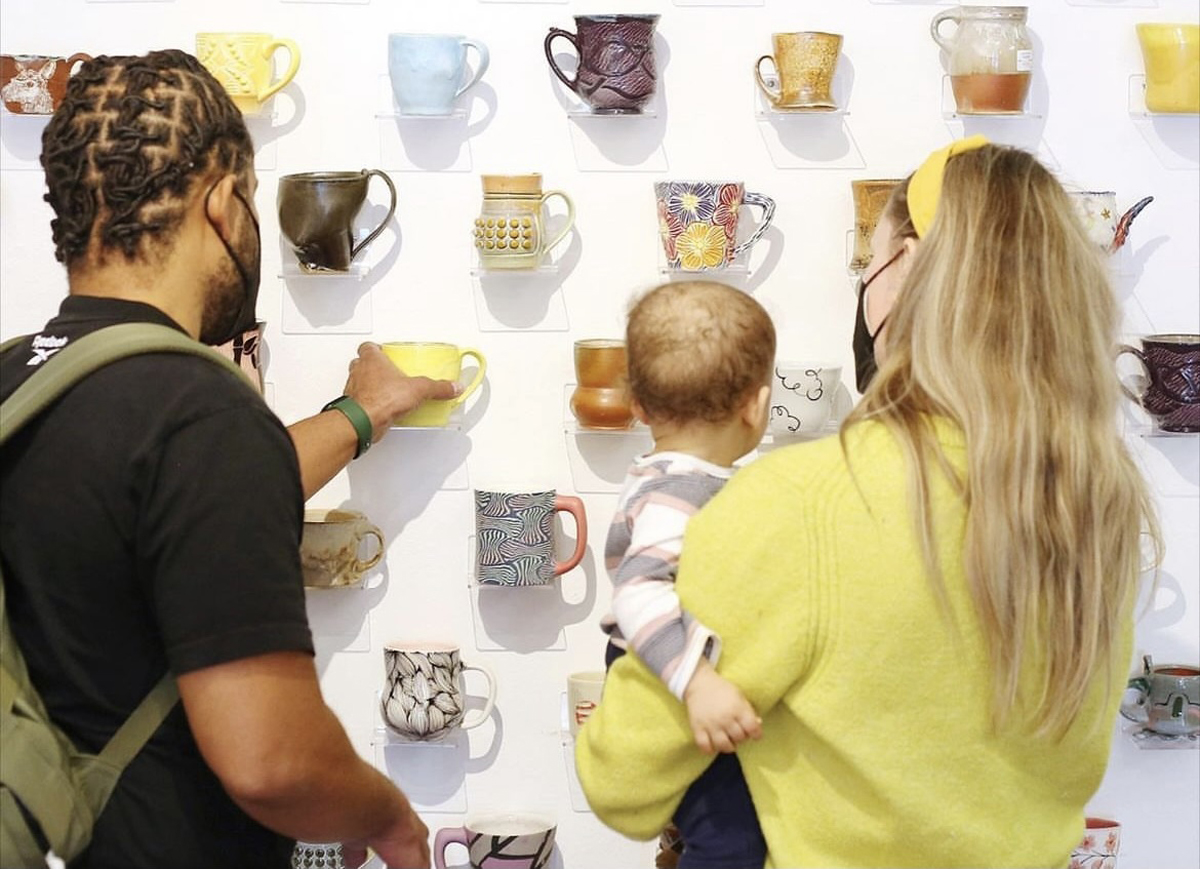 A couple with a baby selects a mug from a vast wall display of artistically decorated vessels. Practical Art is just one of the venues featured in this year's Southwest Holiday Gift Guide from Southwest Contemporary.