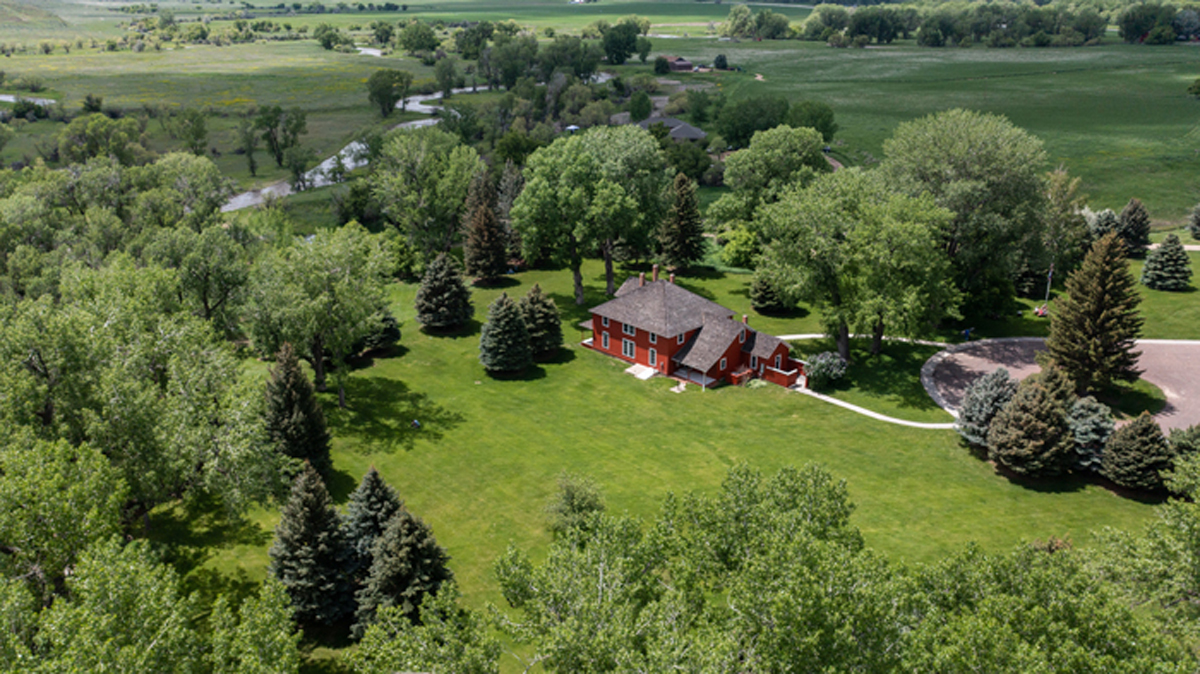 A red house on a sprawling, forested ranch in Wyoming. 