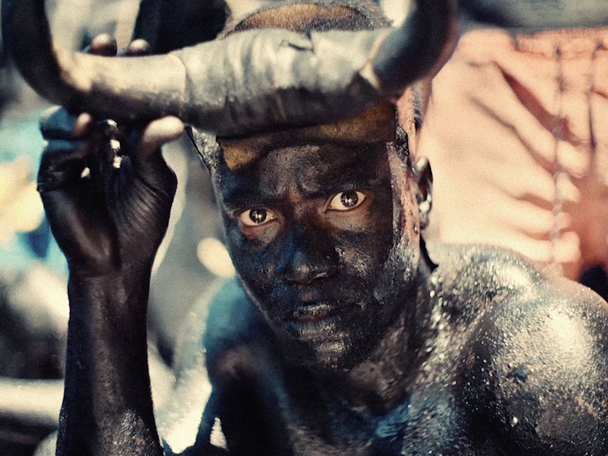 A powerful portrait of a Haitian man holding bull's horns to his head.