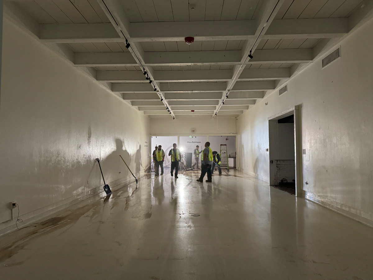 Workers in a floodwater-stained gallery at Roswell Museum. View imagery and read stories from the Roswell Museum flood.