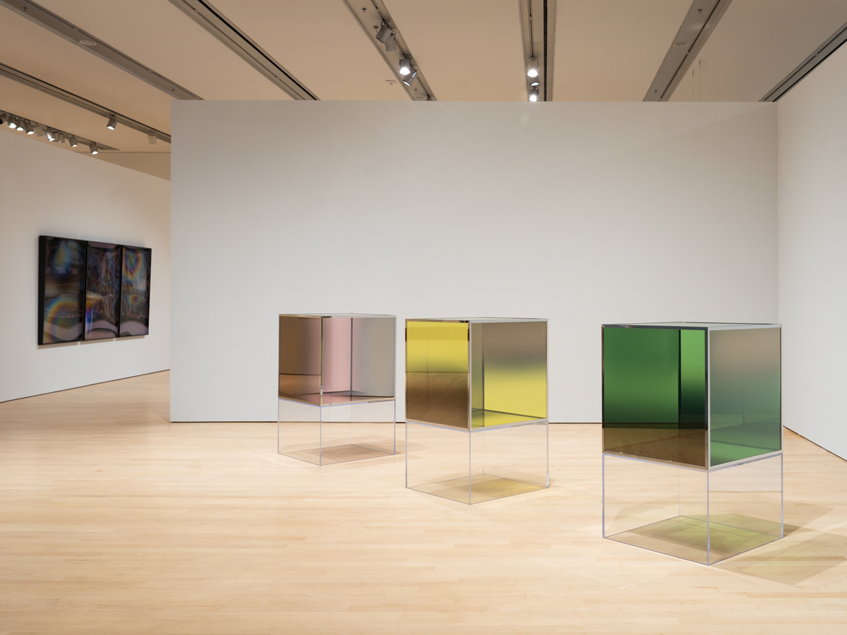 Installation view of a career retrospective by Larry Bell in Phoenix, featuring a row of glass cubes in pink, yellow, and green.