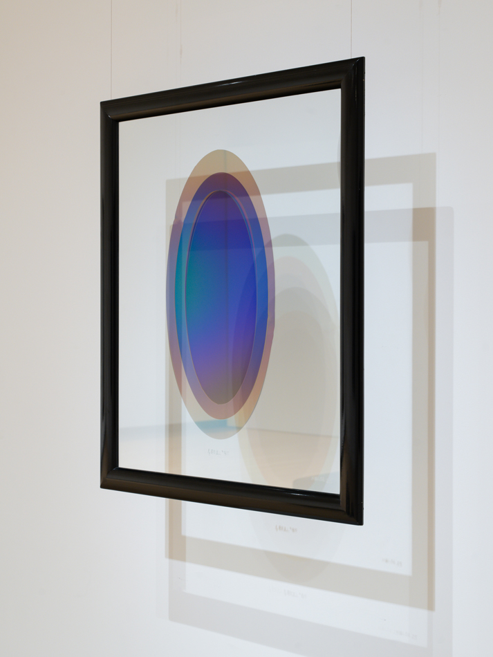 Suspended and framed glass piece by Larry Bell featuring concentric circles in a gradient of purple, green, and blue.