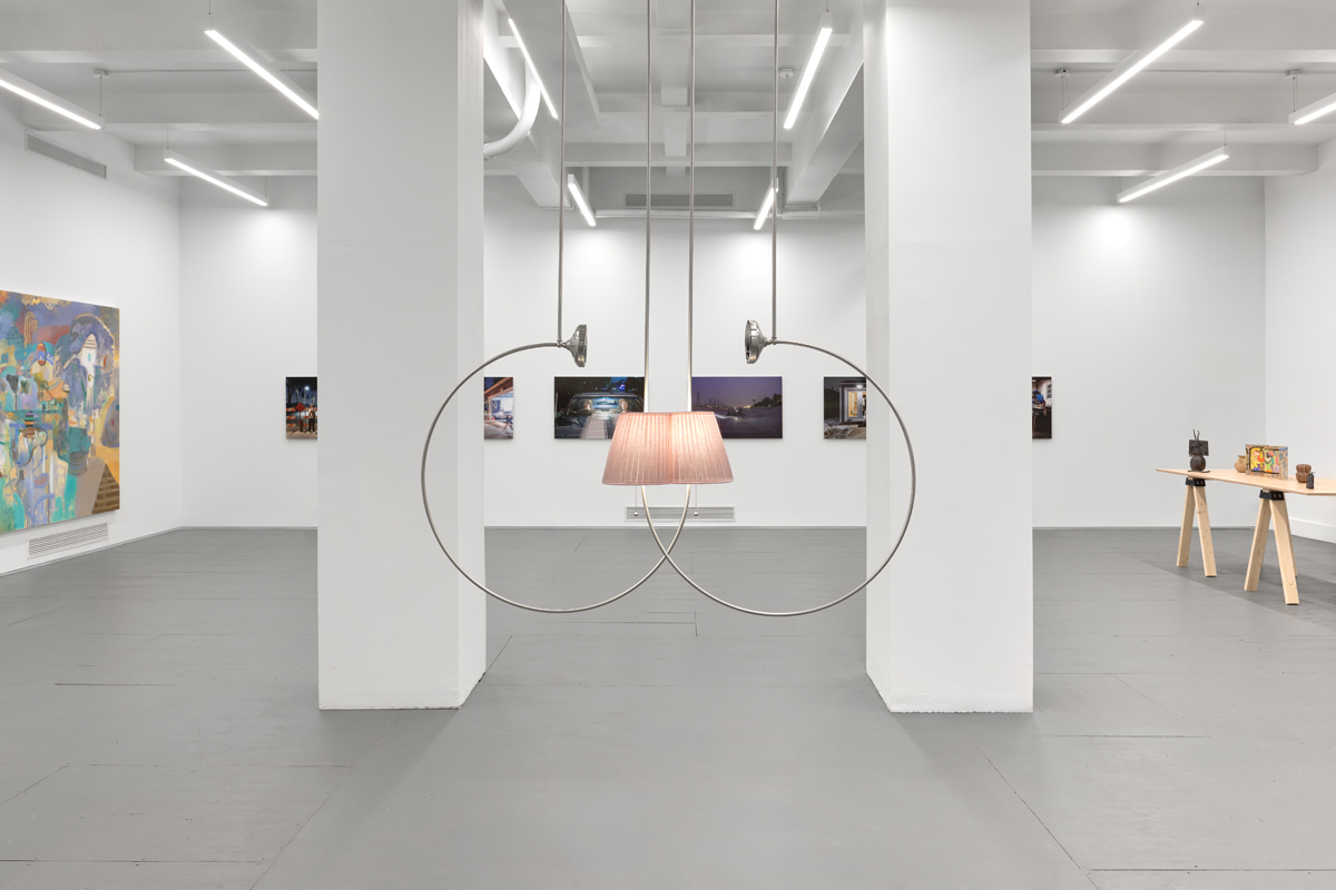 Suspended installation showing a glowing pink lampshade. Curated by Maria Elena Ortiz