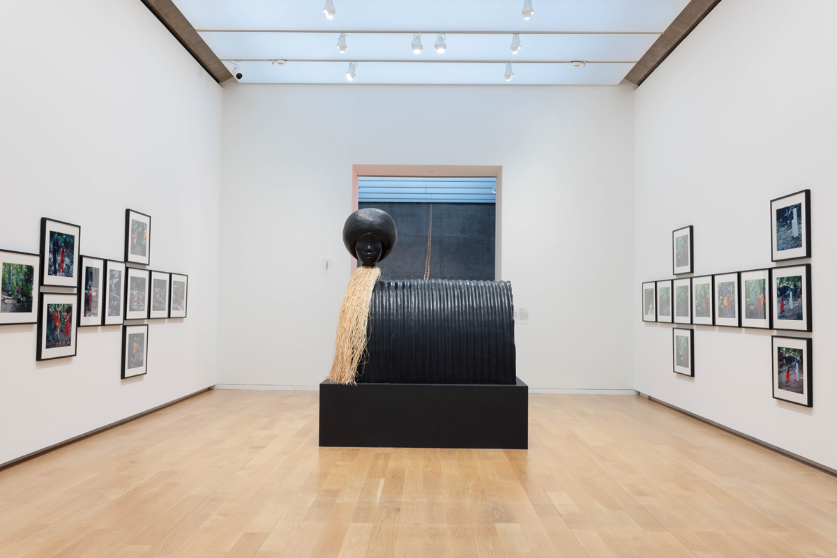 Installation view of a museum show featuring a large-scale figurative sculpture and multiple wall artworks. Curated by Maria Elena Ortiz.