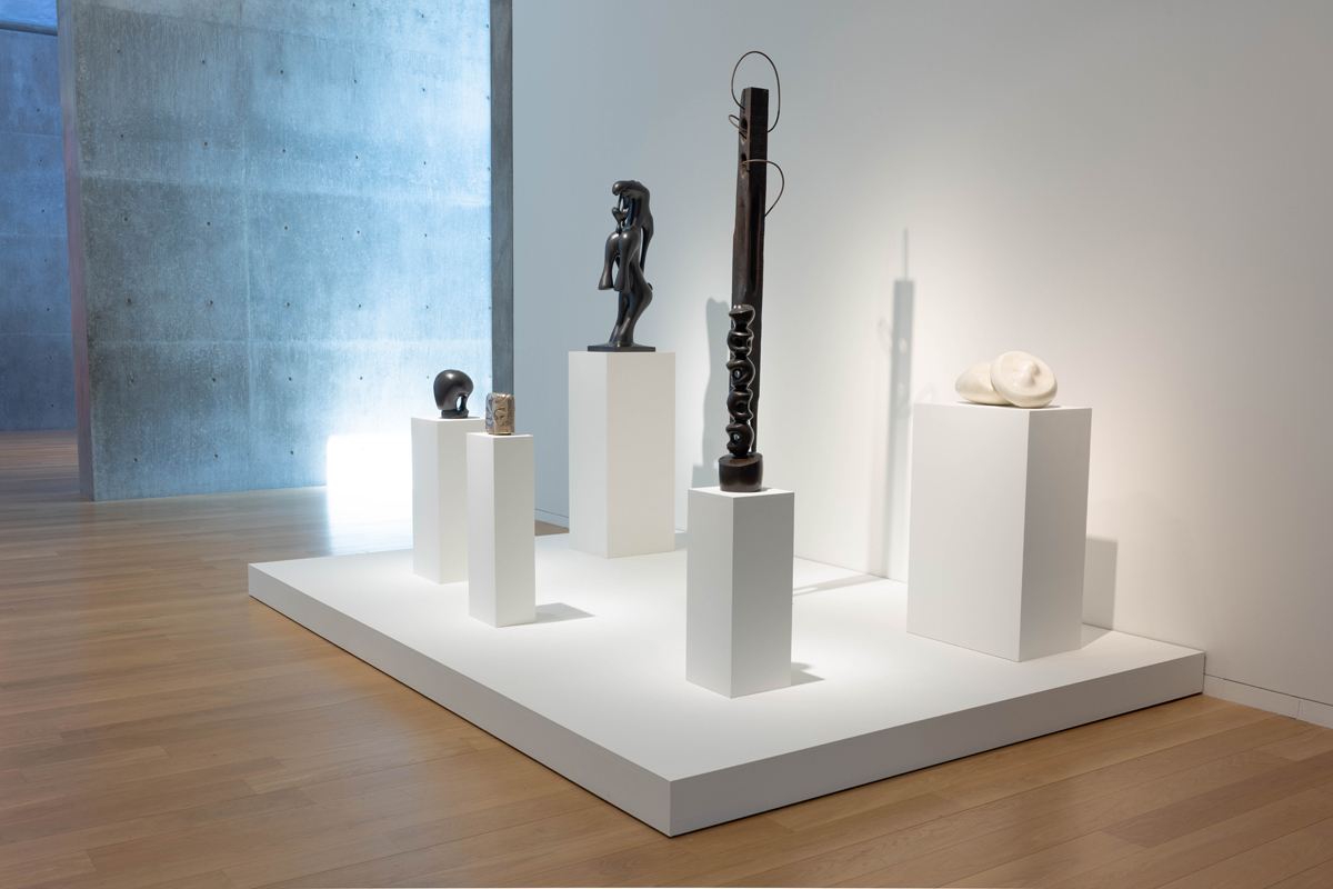 Installation view of tall, angular figurative sculptures in a museum show. Curated by Maria Elena Ortiz.