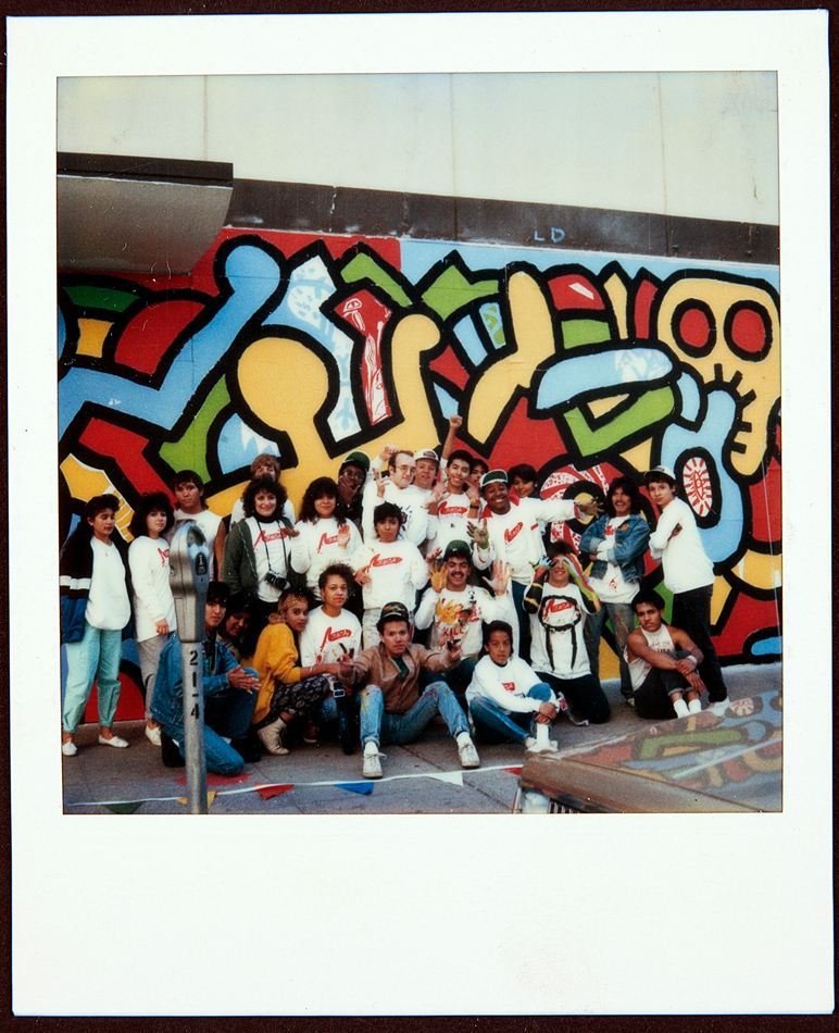 1980s Polaroid showing Keith Haring with Phoenix high school students in front of a colorful mural.