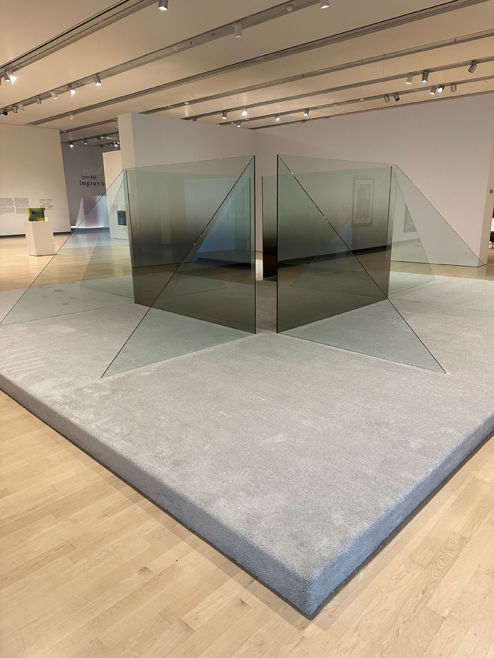 Installation view of a career retrospective by Larry Bell in Phoenix, featuring large-scale, smoky glass forms facing each other to form a square.