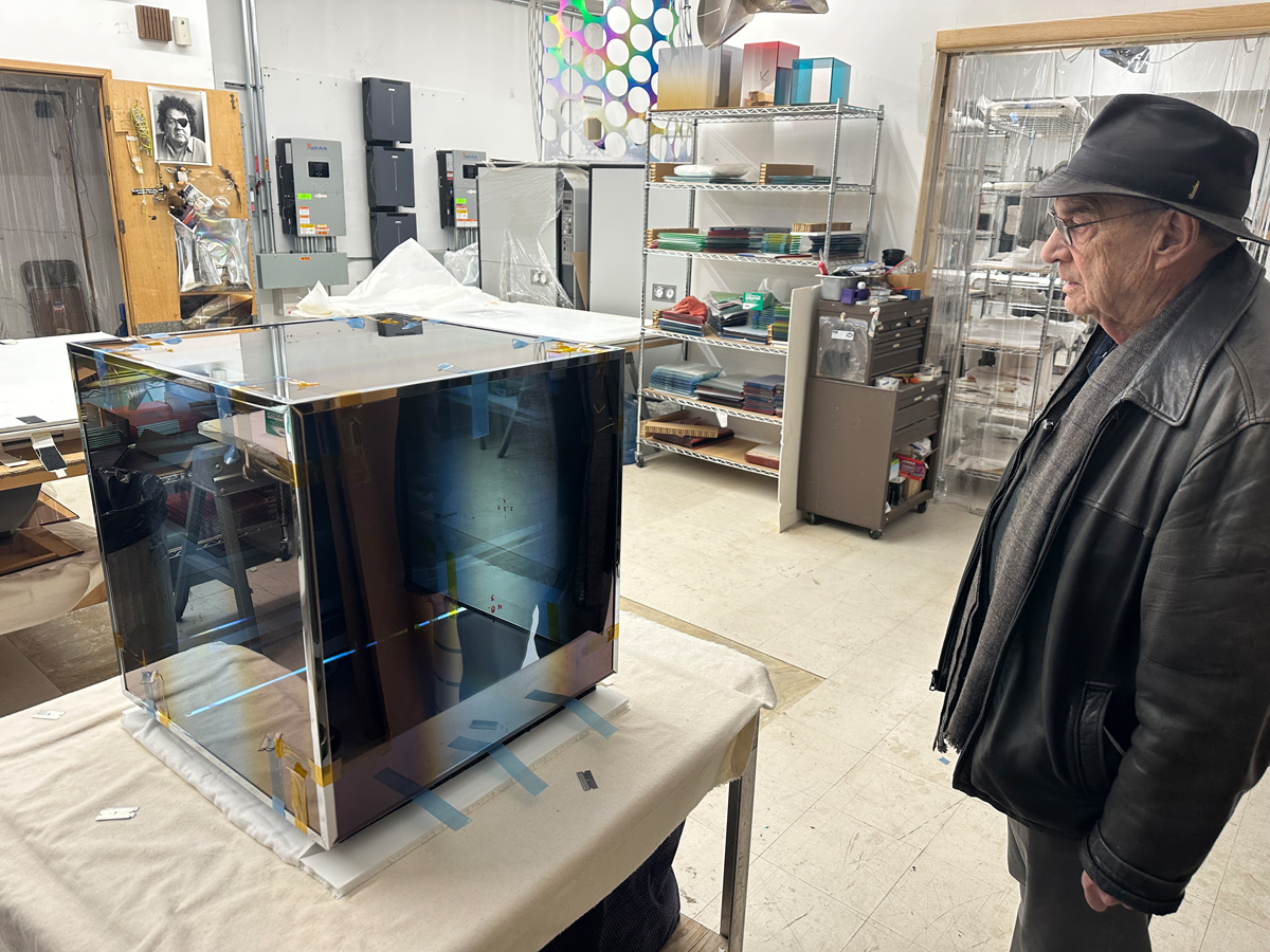 Artist Larry Bell examines a sculptural glass cube in his studio, which characterizes a long-running series—and may be its capstone.