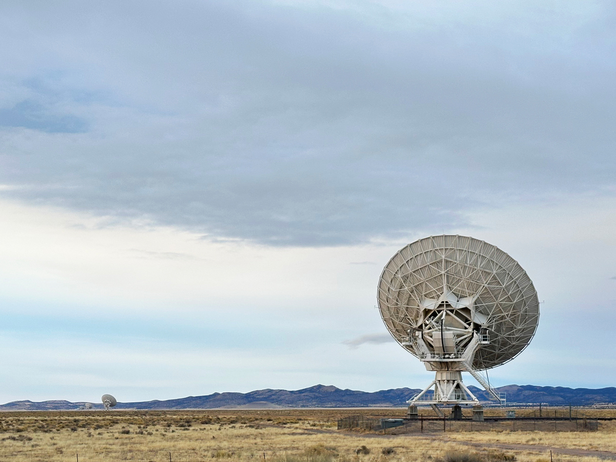 A view of a radar dish in the Very Large Array, with a sweeping New Mexico landscape beyond it.