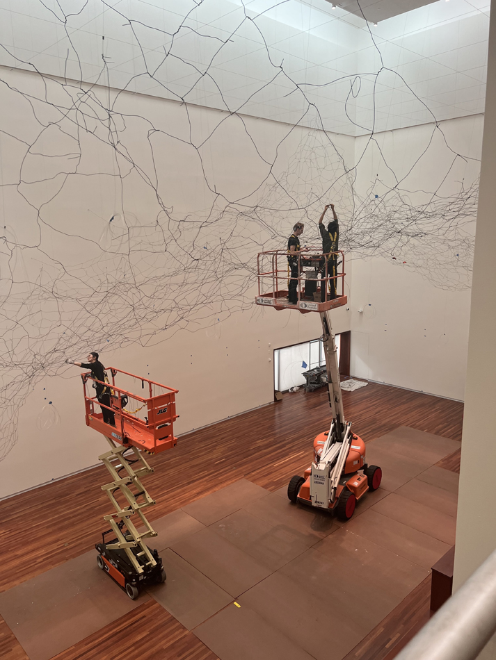 Two lifts allow artists, including Yasuaki Onishi, to attach copper foils to a vast wire frame in an expansive art hall.