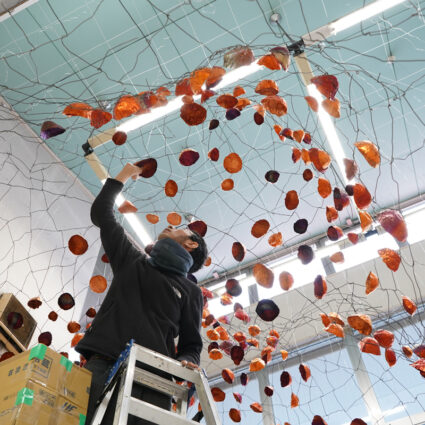 Japanese artist Yasuaki Onishi attaches a copper foil to an undulating wire frame above his head.