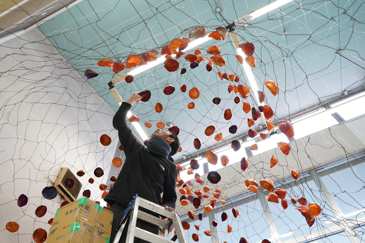 Japanese artist Yasuaki Onishi attaches a copper foil to an undulating wire frame above his head.