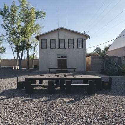 A grey structure with five windows that overlook a long, minimal outdoor dining table. The Chinati Foundation's artist-in-residence program is just one of the Southwest Artist Residencies with spring 2025 submission deadlines.