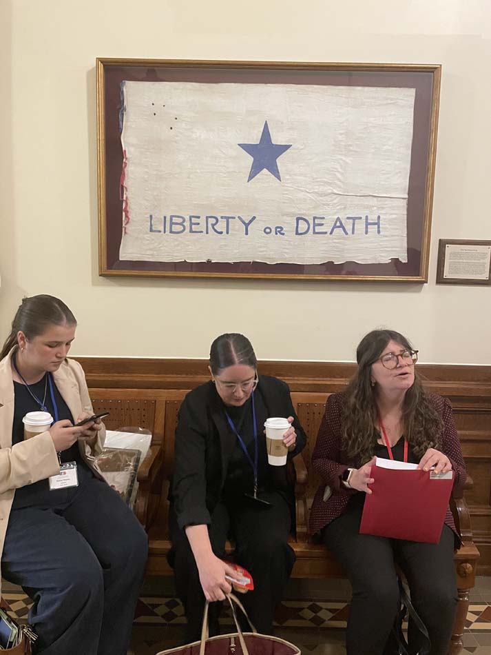 Inside the hallway in the Texas State Capitol, a flag reading Liberty or Death hangs.