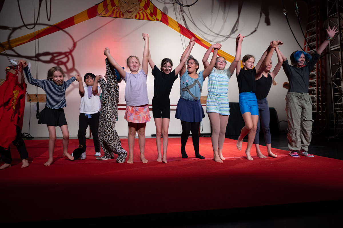 A group of colorfully dressed kids take a bow onstage, surrounded by circus equipment. Wise Fool New Mexico's eviction is just one top Southwest Art Headline January and February 2025.