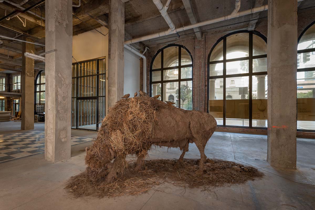 A bison sculpture of welded steel covered with soil and grasses.