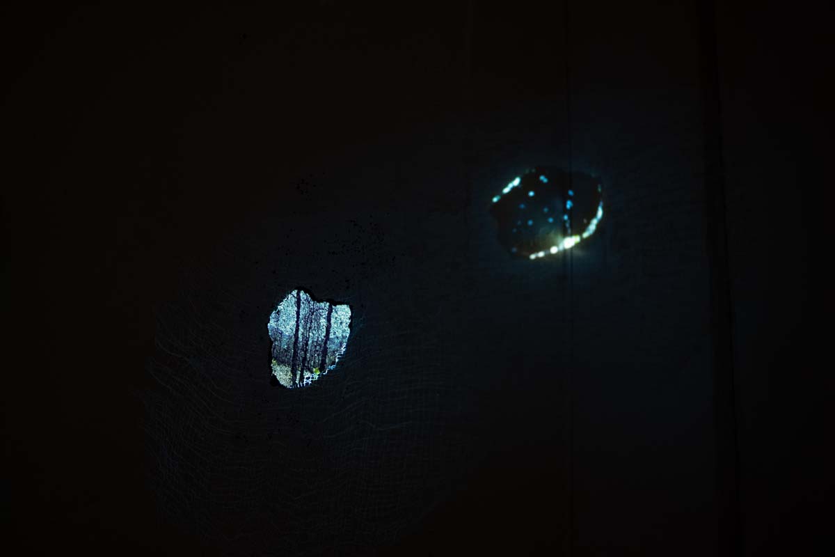 Two small apertures showing a video projection on a black field.