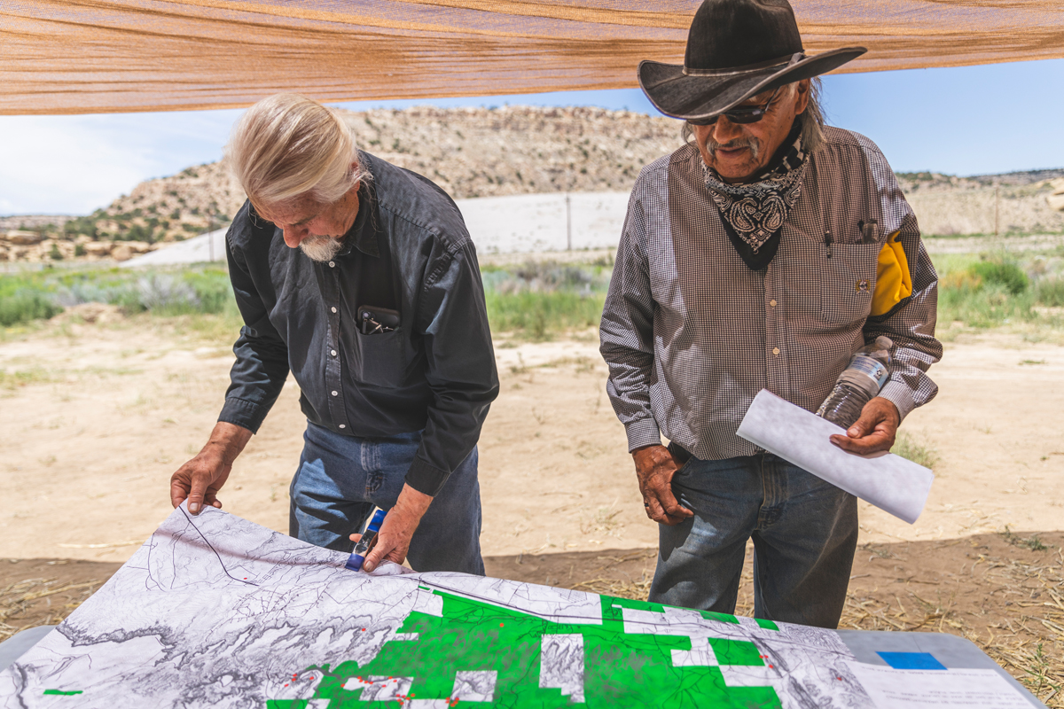 Two men inspect maps for former uranium mining sites.