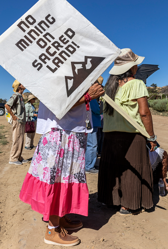 Activist holds a sign that says "No Mining on Sacred Land!"