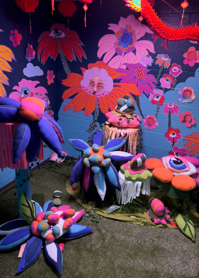 Installation view of Caroline Liu's Chinese Garden, a wonderland of blooming flowers and glowing blood-orange paper lanterns against an indigo sky.