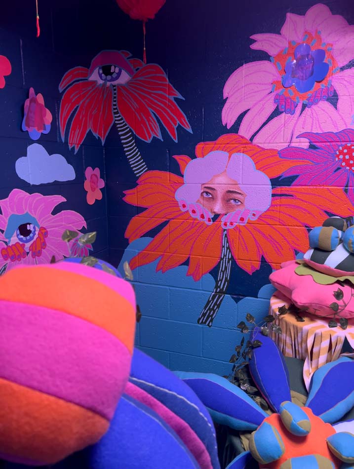 Colorful painting of flowers with a shy face with sleepy, soulful eyes.