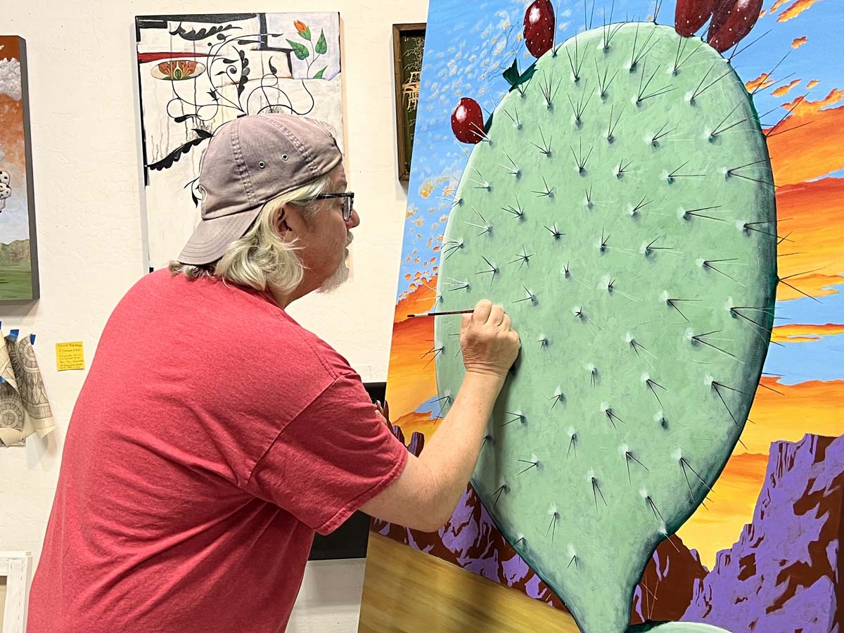 Timothy Chapman painting a cactus pad during an open studio event at Cattle Track