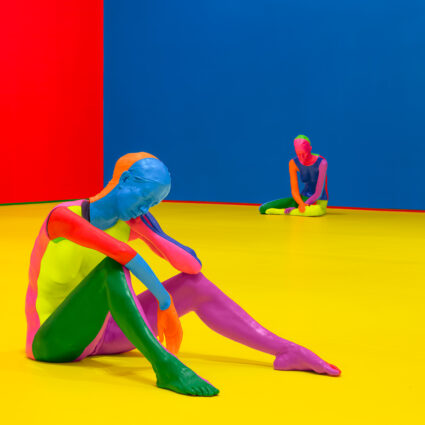 Vibrant wax figures in a color blocked room. Immersive installation by Ugo Rondinone.