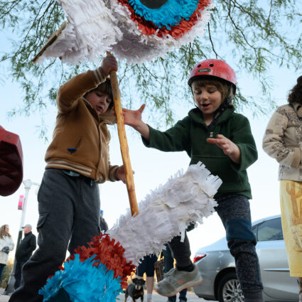 Children play with a piñata at an event by San Antonio's Urgent Care Art.