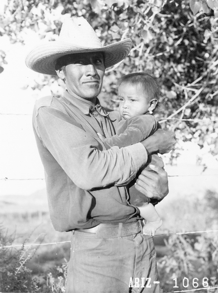 Historical photograph by Milton Snow of a Navajo man holding his baby. Maxwell Museum of Anthropology in Albuquerque is working with the Navajo Nation Museum to fill in the gaps outside the frame.