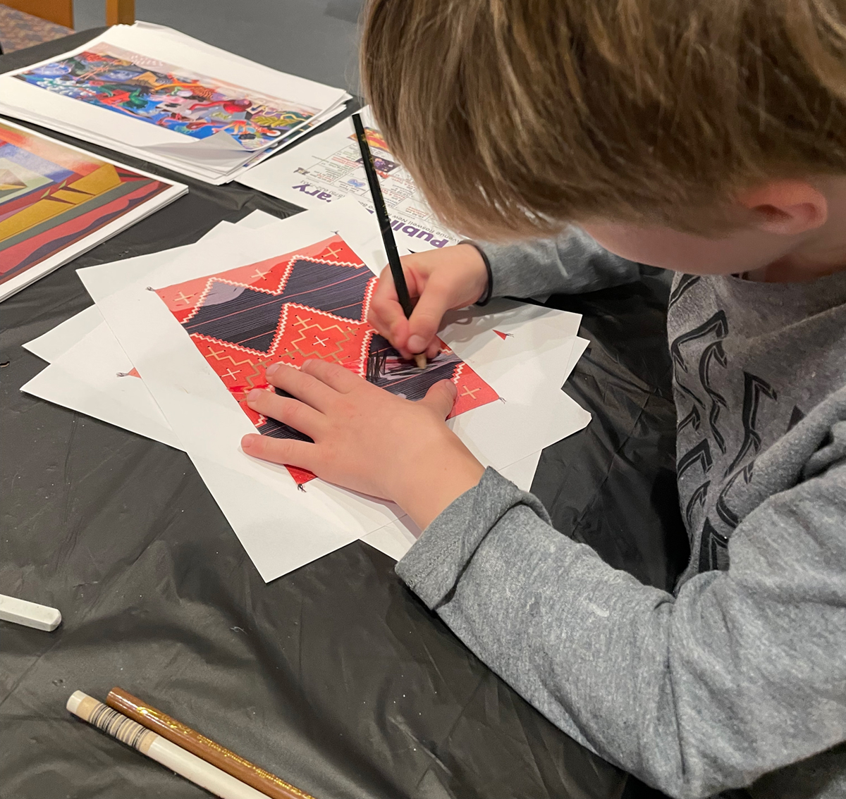 A child Restoring a photocopy of a Navajo blanket (c. 1935-1939) from the Roswell Museum collection, using colored pencil.