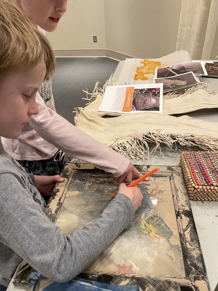 Brushing dried silt off of a framed artwork that had been affected by the October 2024 flood in Roswell, New Mexico.