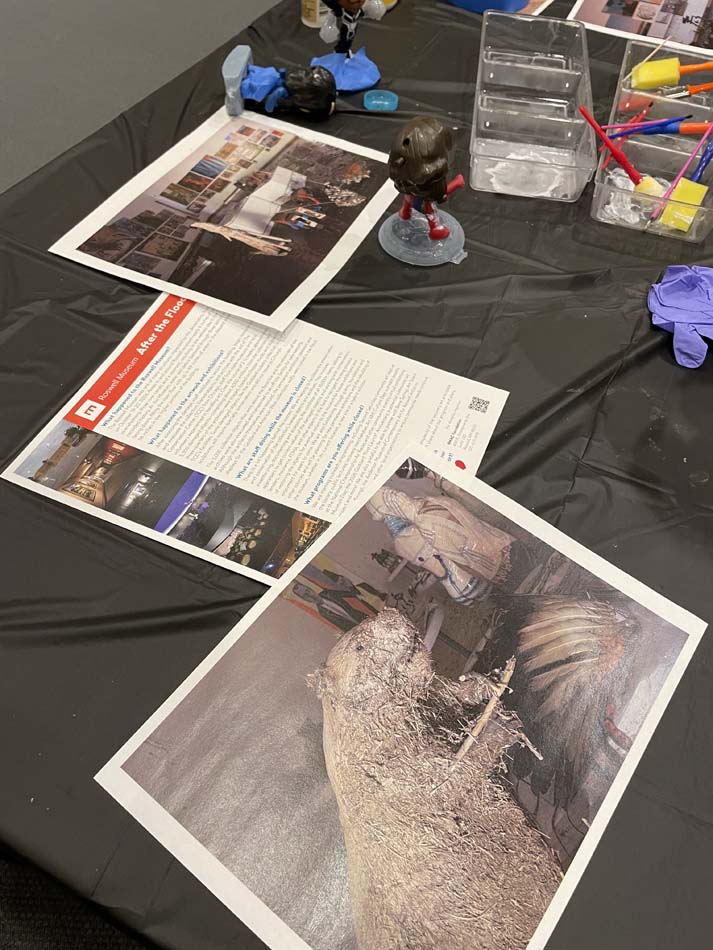 FAQ sheets and photos illustrating the devastation inside the Roswell Museum, including the museum’s taxidermied mascot Biff Beaver covered in mud, set out on a table.