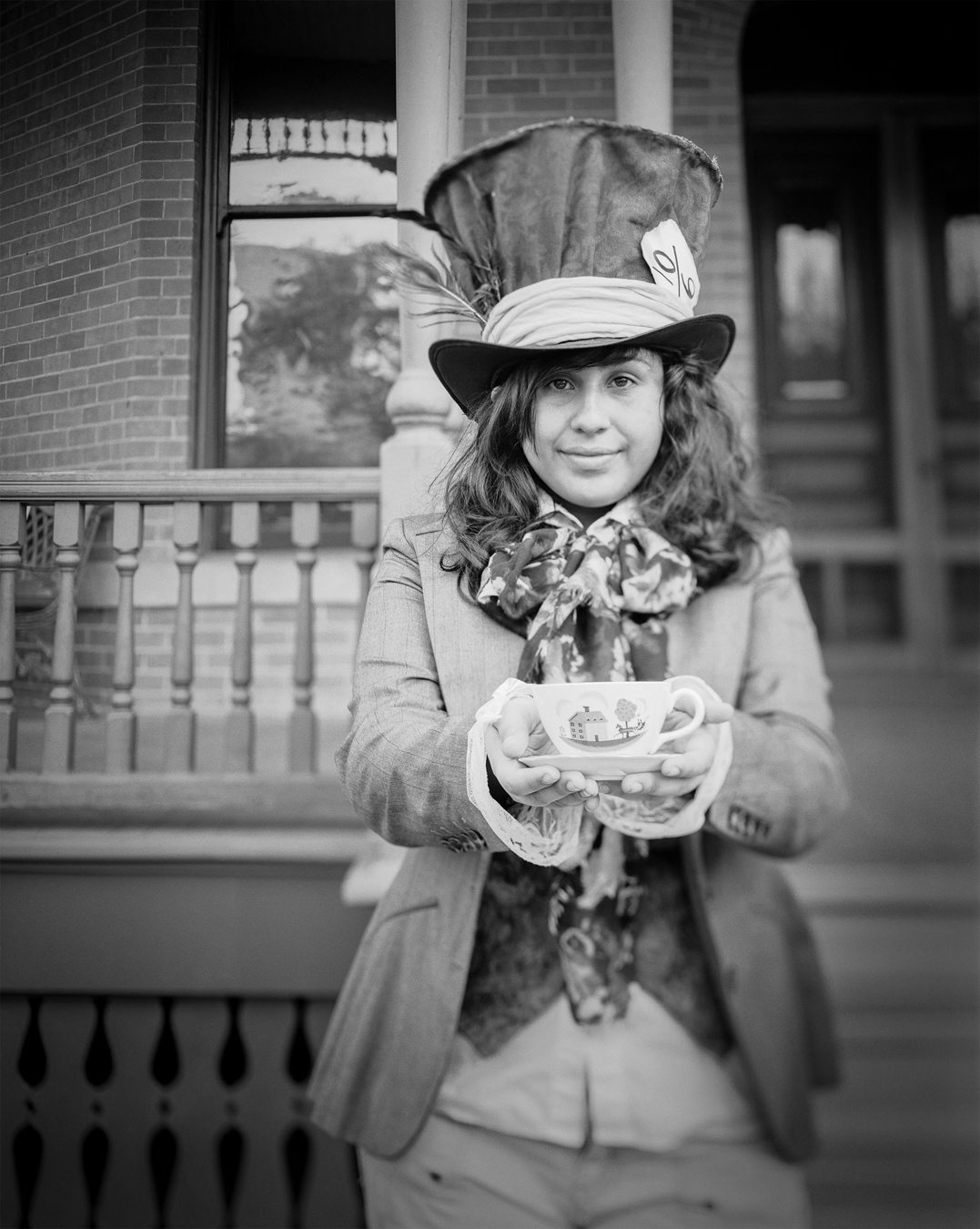A cosplayer dressed as the Mad Hatter holds out a teacup.