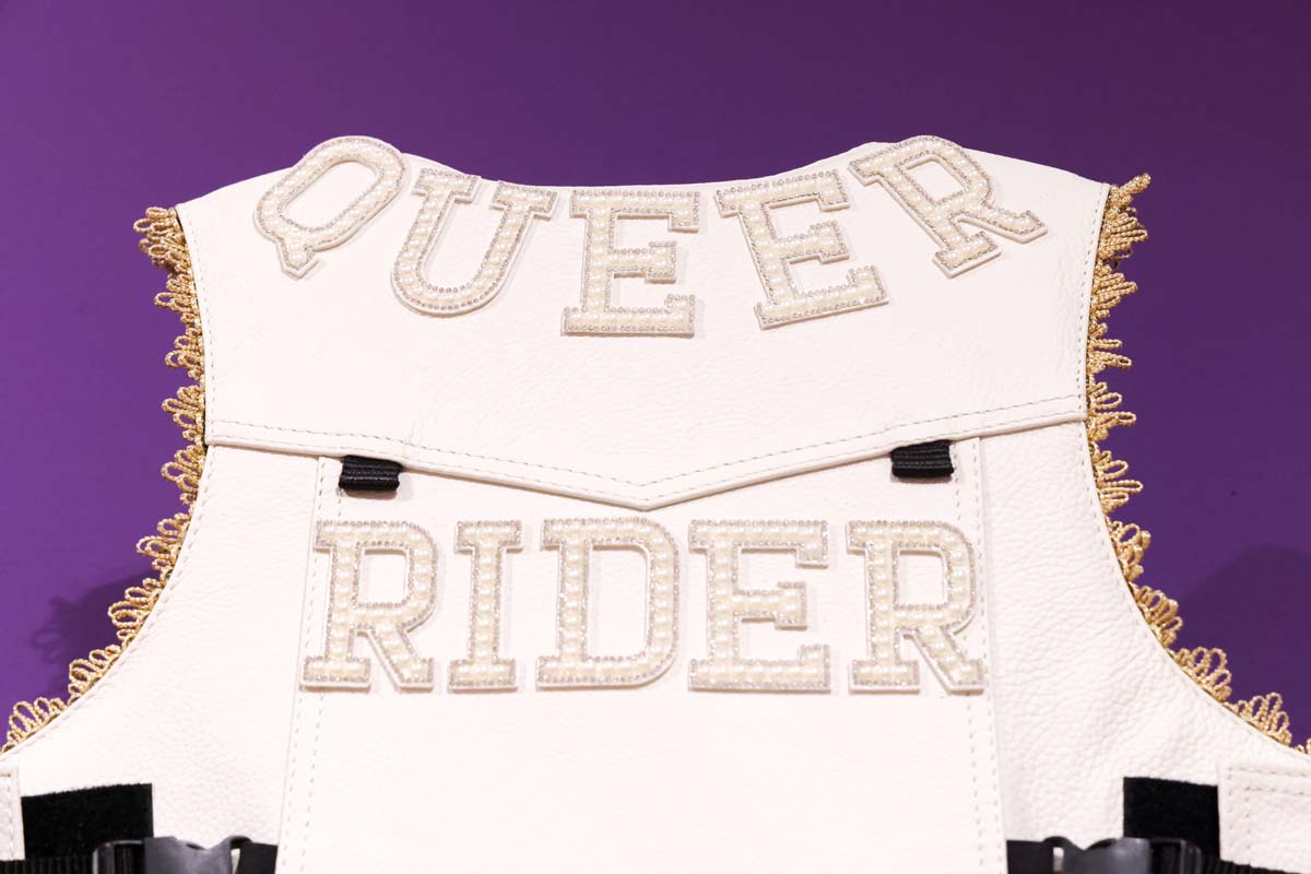 White leather vest with the words "QUEER RIDER"